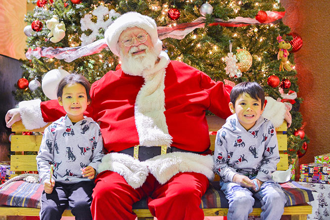 In this Dec. 5, 2024, photo, two young guests pose for a photo with Santa Claus during Holiday in New Mexico at The University of New Mexico-Gallup.