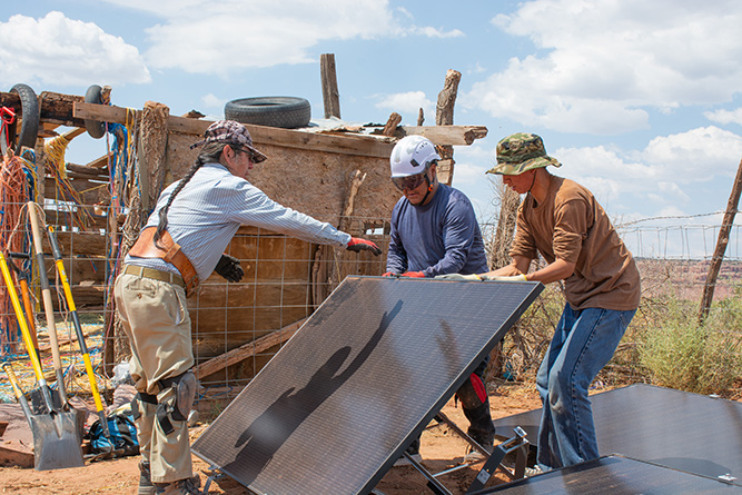 From left: UNM-Gallup solar technician students Travis Kaskalla, Leonard Ross, and Terrence Stewart work together on a solar panel at a home in Zuni on Aug. 22, 2025. 