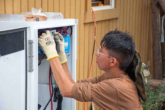 UNM-Gallup solar technician student Terrence Stewart works on the wiring of the solar panel’s system inverter at a home in Zuni on Aug. 22, 2025.