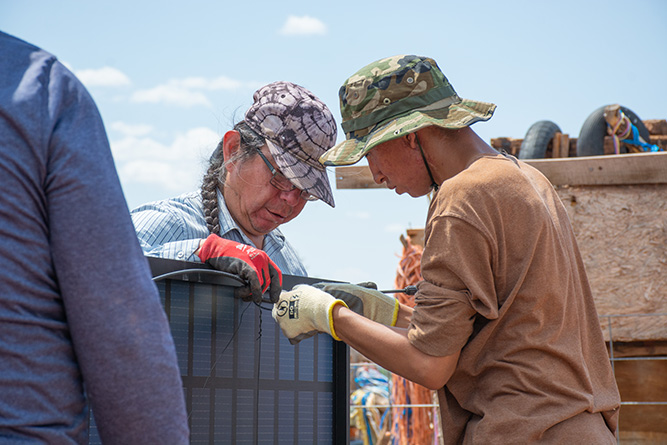 UNM-Gallup solar technician students Travis Kaskalla, left, and Terrence Stewart work together on a solar panel at a home in Zuni on Aug. 22, 2025.