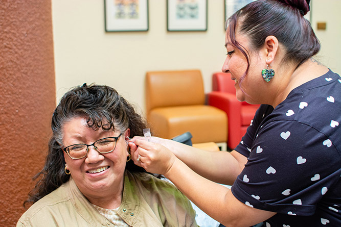 Michelle Skersick, a certified peer support worker with the City of Gallup, applies acupuncture needles to the ears of Administrative Assistant II Michelle Palacios during The University of New Mexico-Gallup's Campus Safety Fair in the Gurley Hall Commons on Thursday, Sept. 18, 2025.