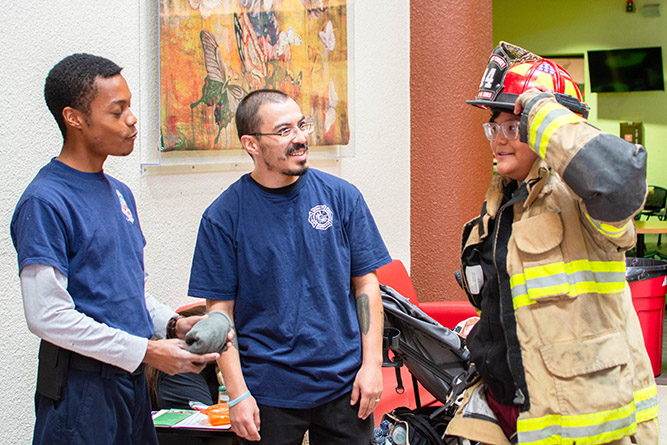 A student tries on McKinley County firefighting gear during The University of New Mexico-Gallup's Campus Safety Fair in the Gurley Hall Commons on Thursday, Sept. 18, 2025.