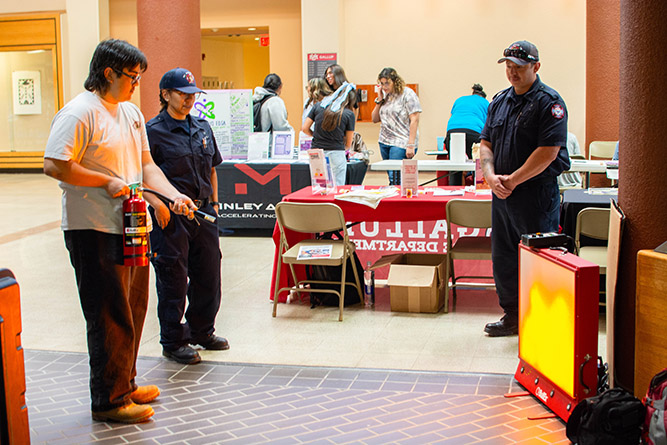 A student learns how to put out a fire using a fire extinguisher simulator during The University of New Mexico-Gallup's Campus Safety Fair in the Gurley Hall Commons on Thursday, Sept. 18, 2025.