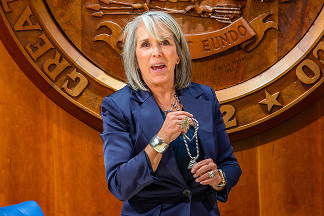 New Mexico Gov. Michelle Lujan Grisham showcases a necklace with a pendant commemorating the Route 66 centennial after a meeting with Gallup-McKinley County leaders in Santa Fe on Wednesday, Feb. 4, 2026.